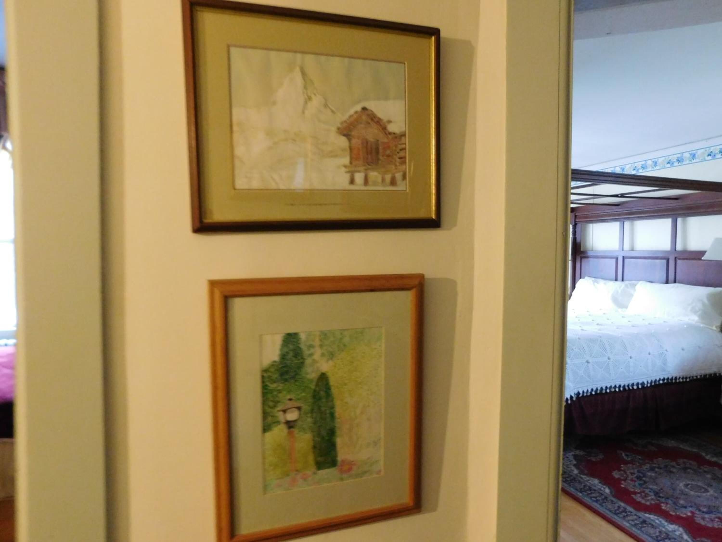 A room with a bed, a framed painting, and a window.