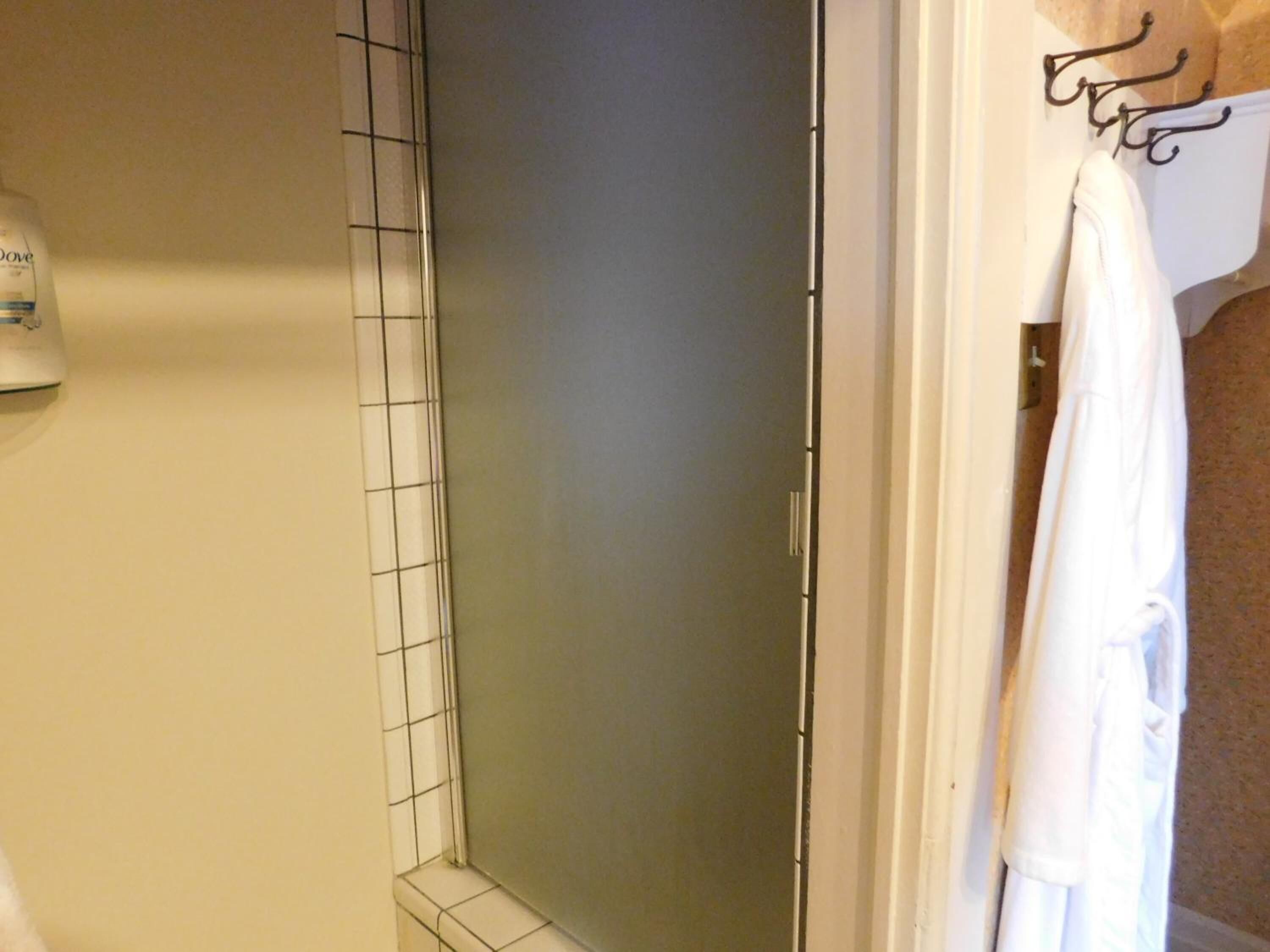 A bathroom with a shower, a towel rack, and a bottle of Dove soap.