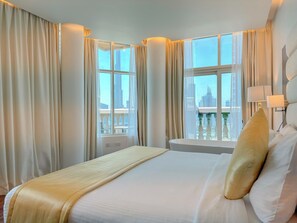 Une chambre d’hôtel avec un grand lit, deux fenêtres avec des rideaux, une vue sur la ville et un balcon.