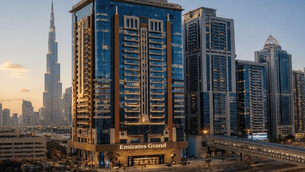 A high-rise building with a prominent sign reading 'Emirates Grand.' - Emirates Grand Hotel (Dubai)
