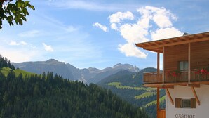 A mountain lodge with a wooden balcony and a view of the surrounding forest and mountains. - Hotel Pider (La Valle)