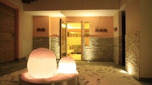 A snow-covered indoor area with a heated snow sculpture centerpiece, stone walls, and a visible door leading to another room. - Hotel Pider (La Valle)
