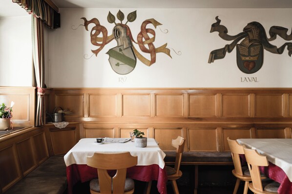 Un comedor con paneles de madera, una mesa con mantel blanco y dos sillas.