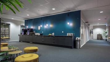 A modern office space with a reception desk, seating area, and a corridor leading to other rooms.