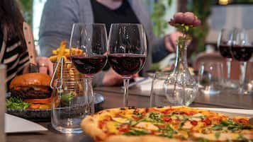 A dining table with a burger, fries, pizza, and wine glasses.