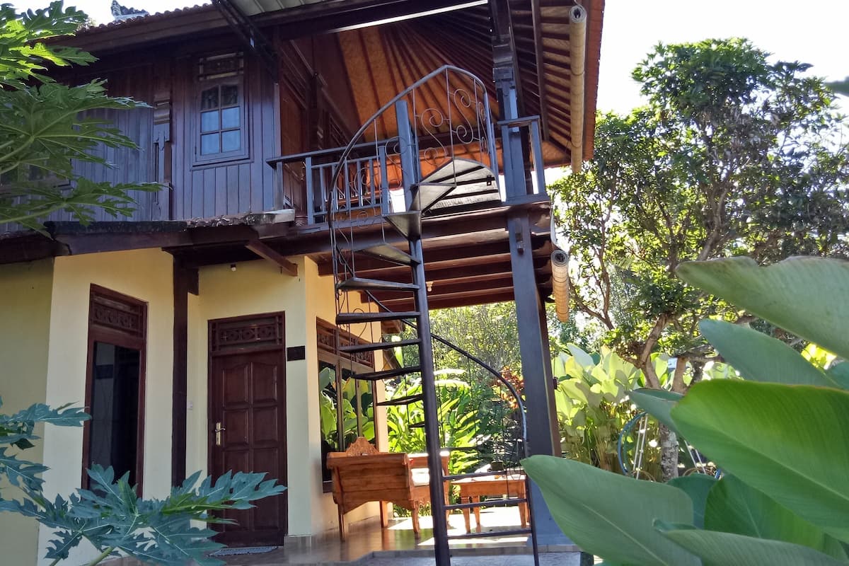 A wooden house with a balcony, a staircase, and a door.