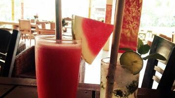 Two drinks on a table with a wooden ceiling and a view of the outdoors.