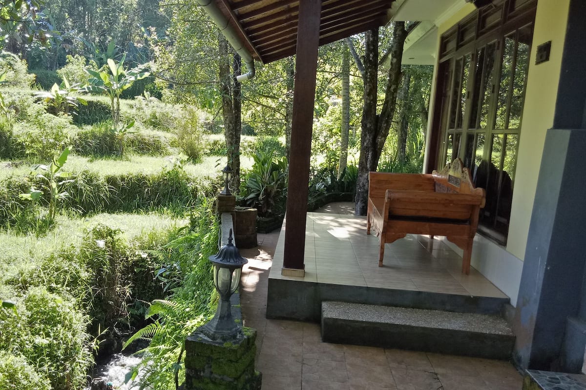 A covered outdoor area with a bench and steps leading to a building.
