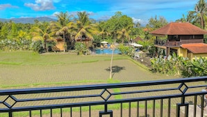 Vista de una zona residencial con piscina, palmeras y casas con tejados rojos.