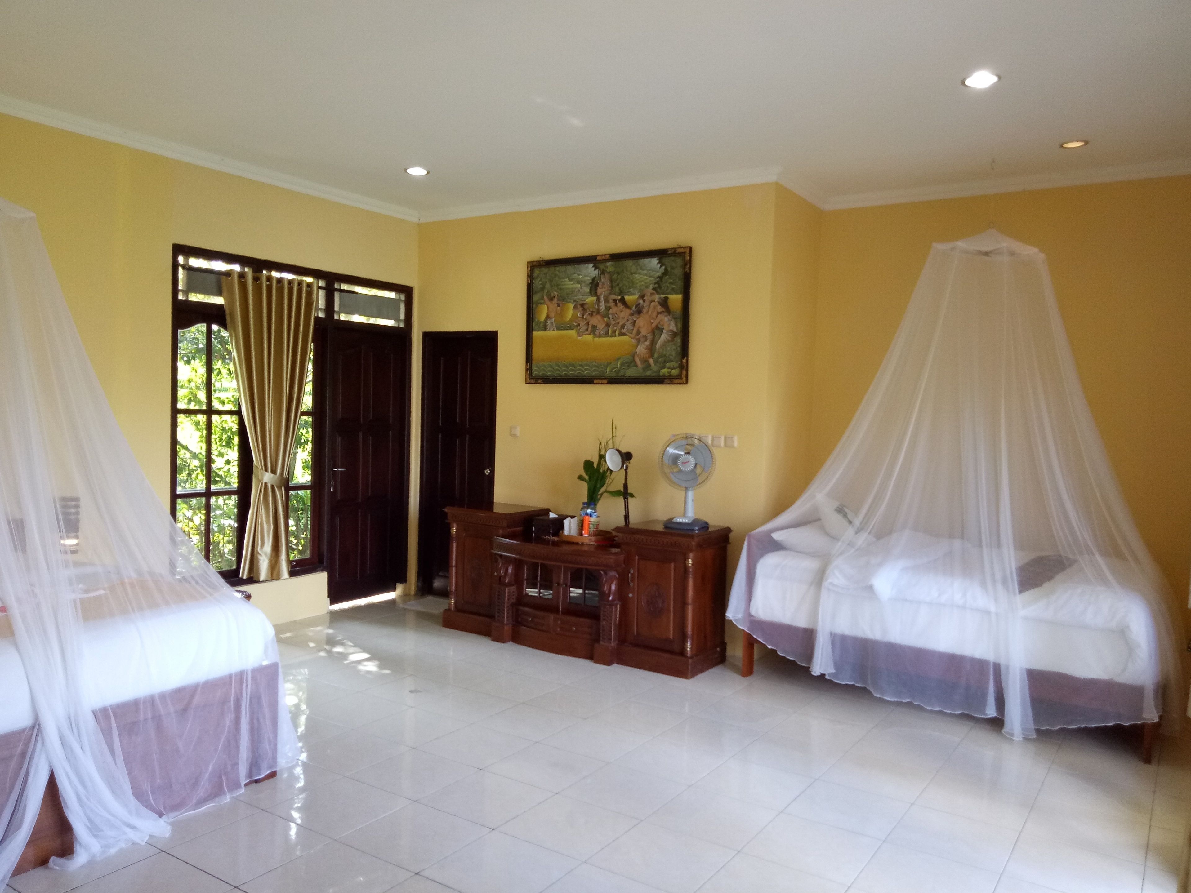 A room with two beds, each covered with a white canopy, a wooden cabinet, a painting on the wall, and a window with curtains.