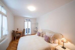A bedroom with a bed, bedside table, lamp, and a desk with chairs. - Hotel Hammer (Schwarzenberg)