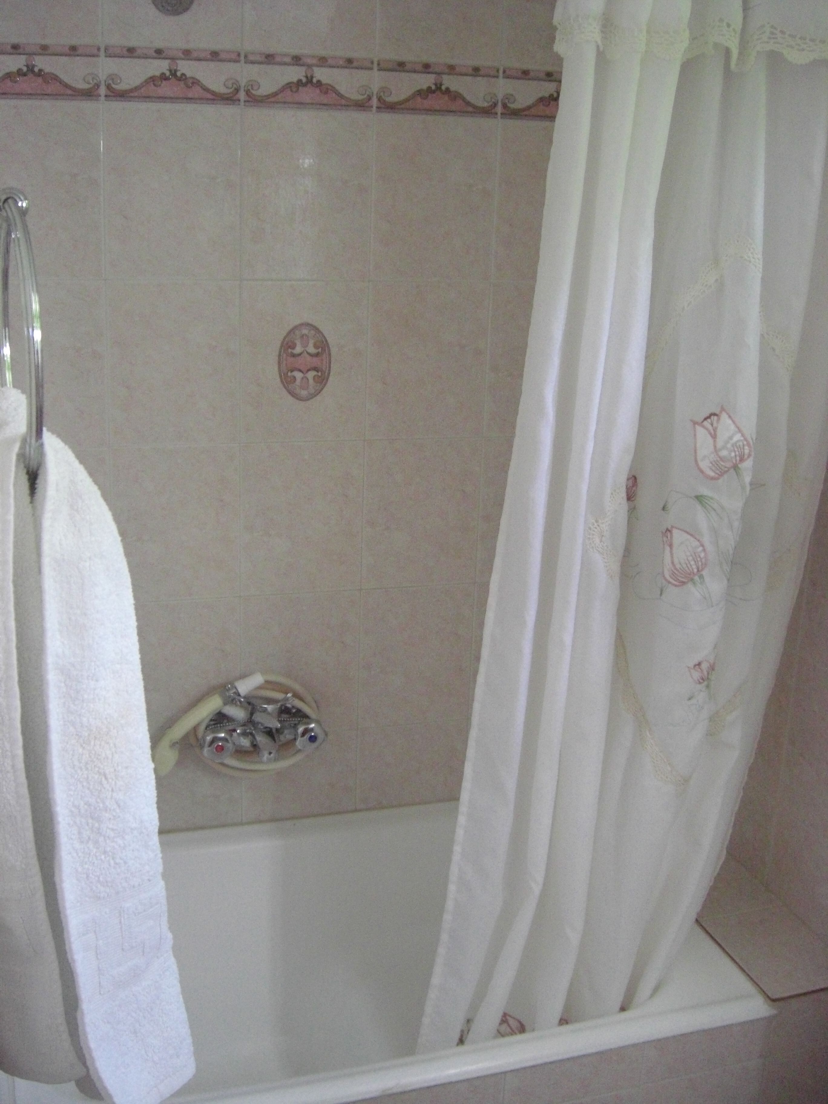 A bathroom with a bathtub, a shower curtain, and a towel rack.