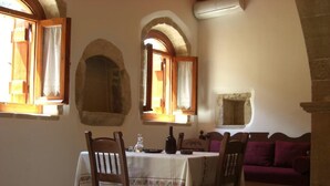 A dining area with a table set for four, wooden chairs, and a purple sofa in the background. - Patriko Traditional Residence (Apokoronas)