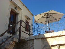 A building with a stone staircase, a metal railing, and a large umbrella providing shade.