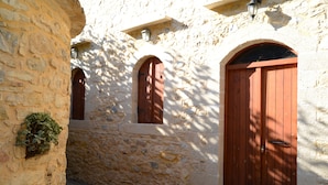 A stone building with arched windows and a wooden door. - Patriko Traditional Residence (Apokoronas)
