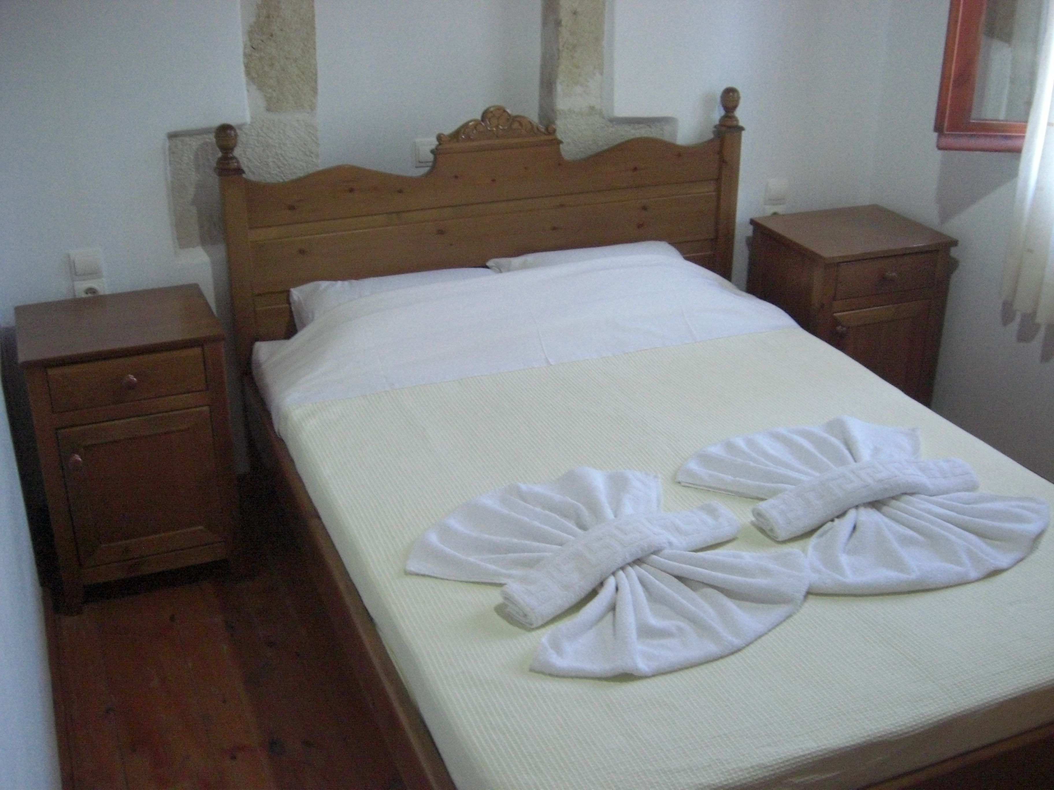 A single bed with a wooden headboard, two nightstands, and a wooden dresser.
