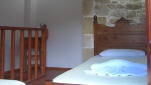 A bedroom with a wooden bed, a stone wall, and two wall-mounted lights. - Patriko Traditional Residence (Apokoronas)
