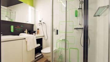 Un baño moderno con cabina de ducha de vidrio, un lavabo blanco y un inodoro.