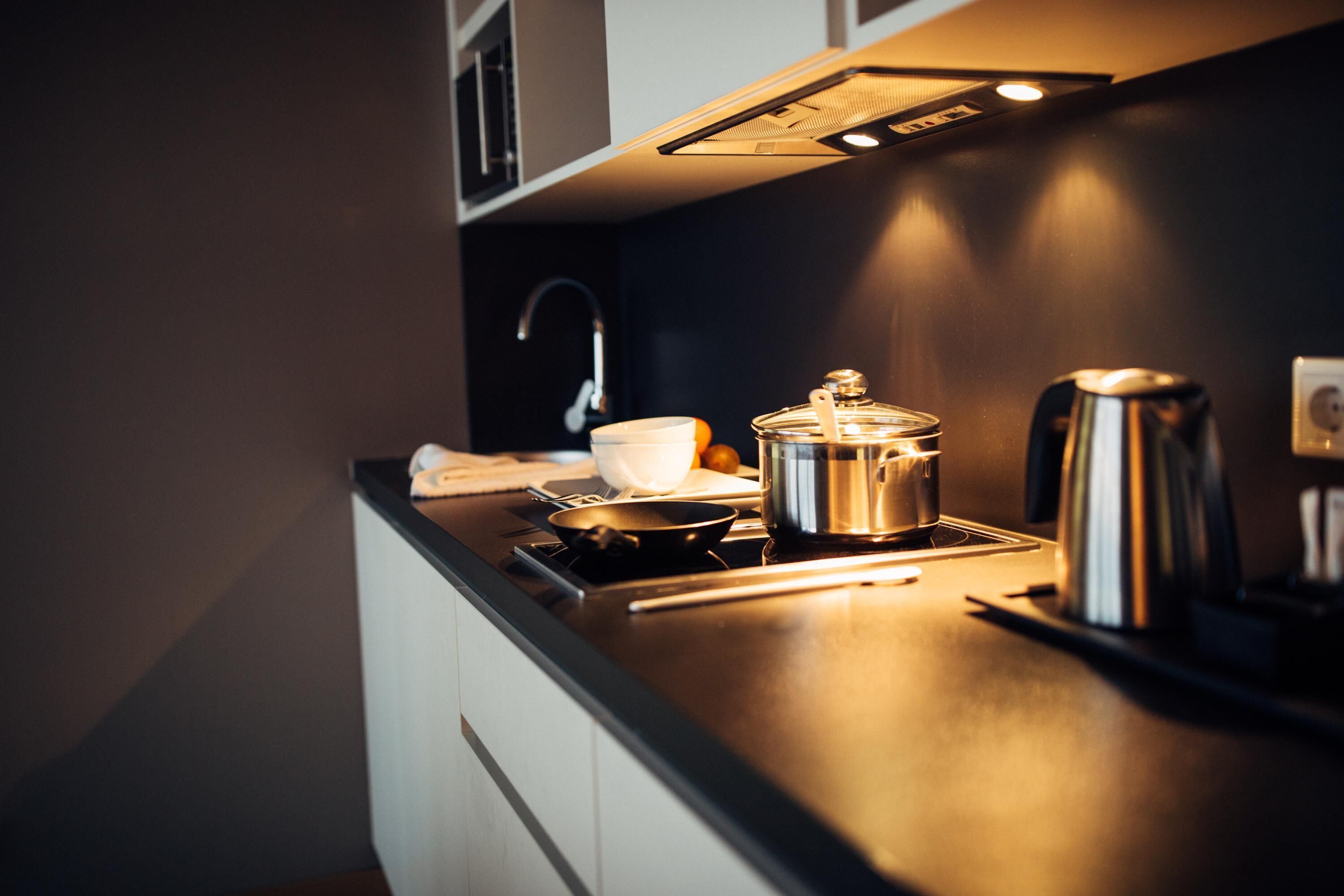A modern kitchen with a stove, a kettle, and a coffee maker.