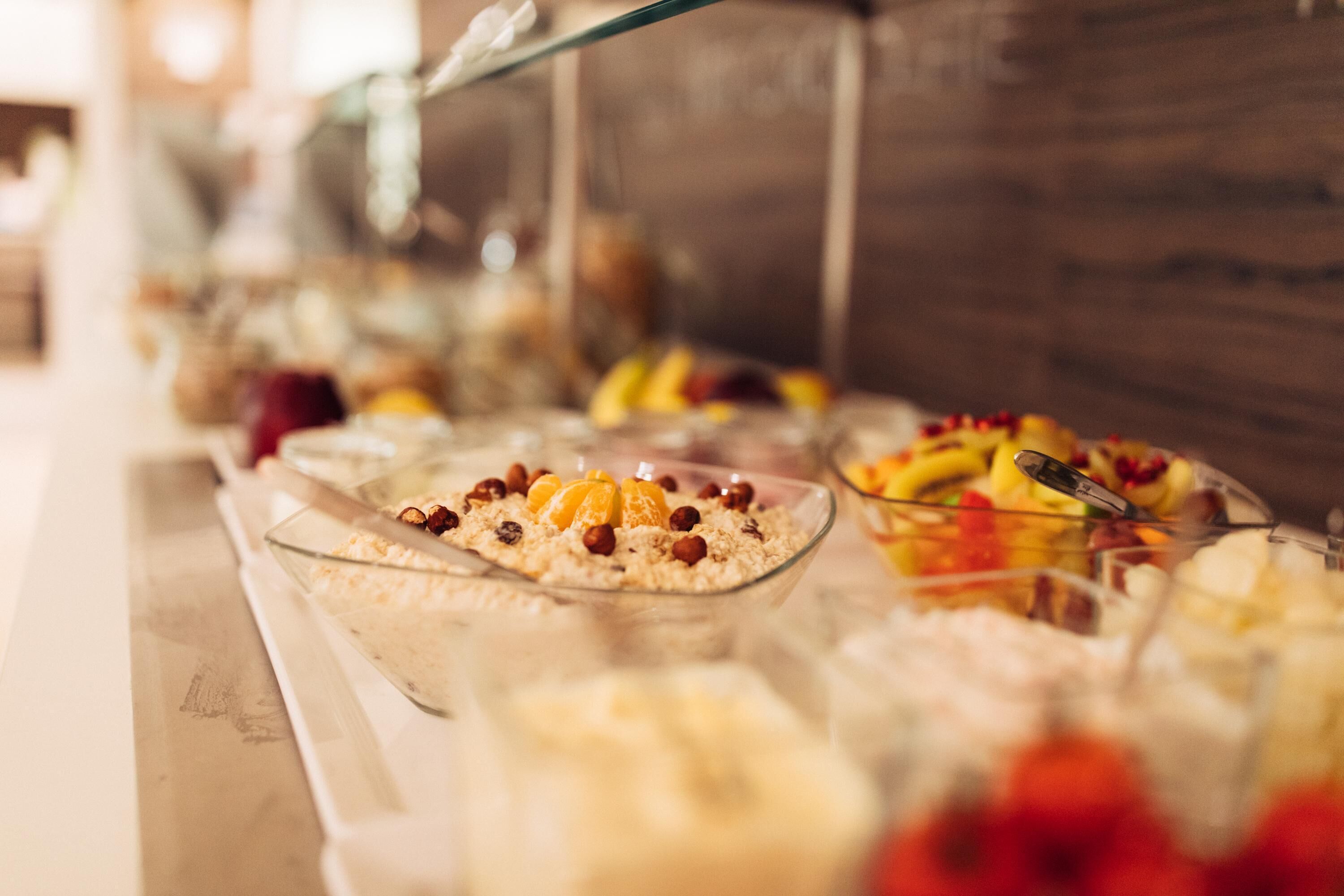 A buffet with various dishes, including fruits and desserts, arranged on a counter.
