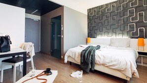 A modern hotel room with a bed, bedside lamps, a desk, and a chair. - harry’s home München Moosach hotel & apartments (Munich)