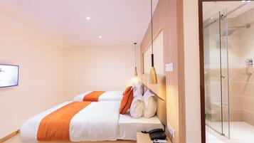 A hotel room with two beds, a shower area, and a mounted television.