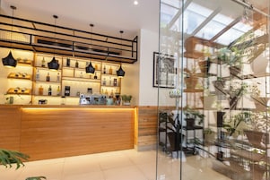 Una zona de bar con estanterías llenas de botellas, una máquina de café y luces colgantes.