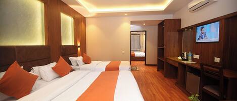 Habitación de hotel con dos camas, televisión y escritorio con cafetera.