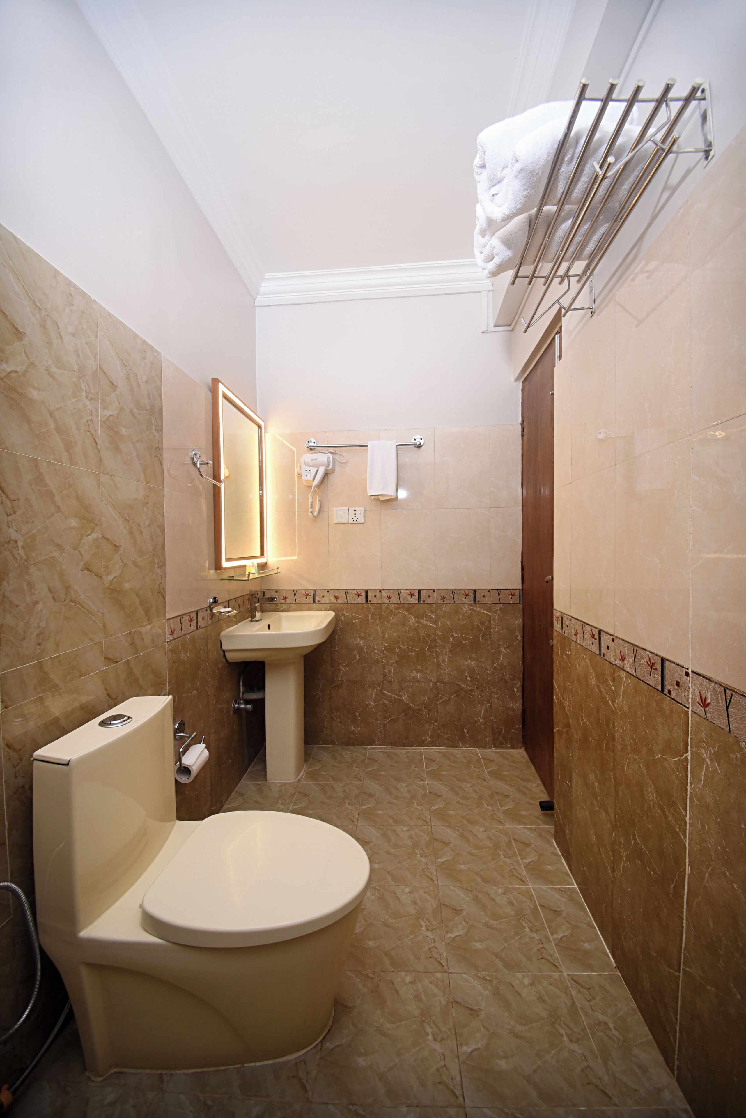 Un baño con inodoro, lavabo y toallero.