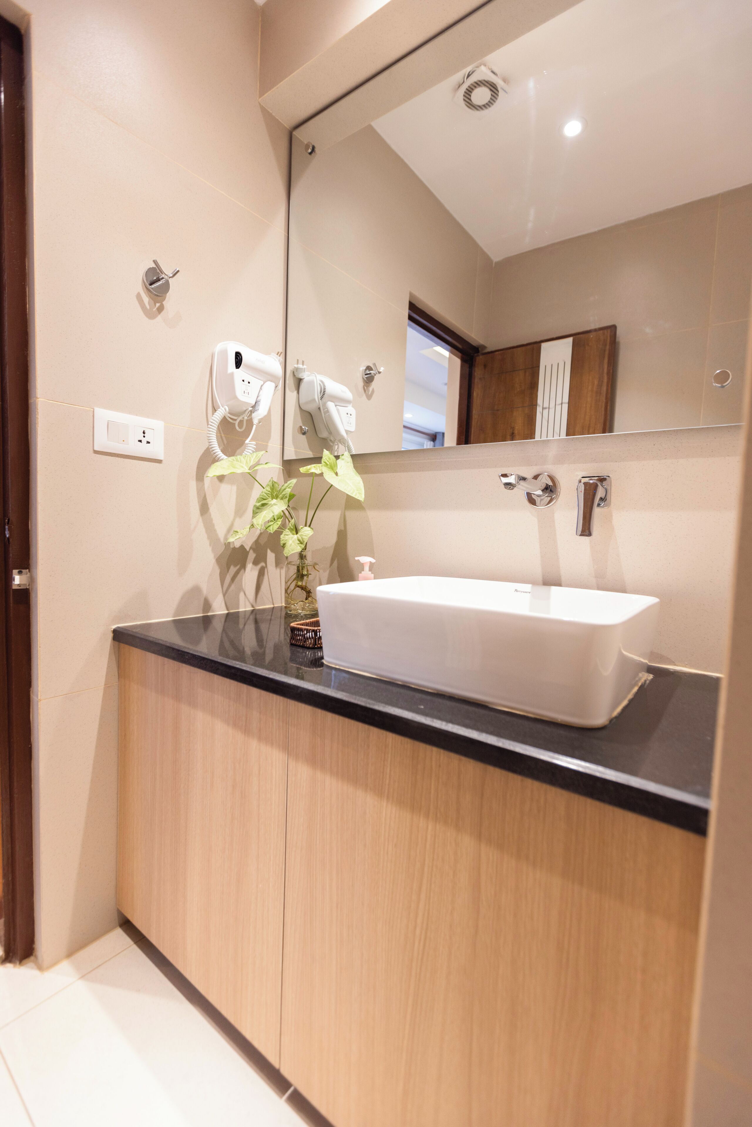 A modern bathroom with a large mirror, a white sink, and a wooden vanity.