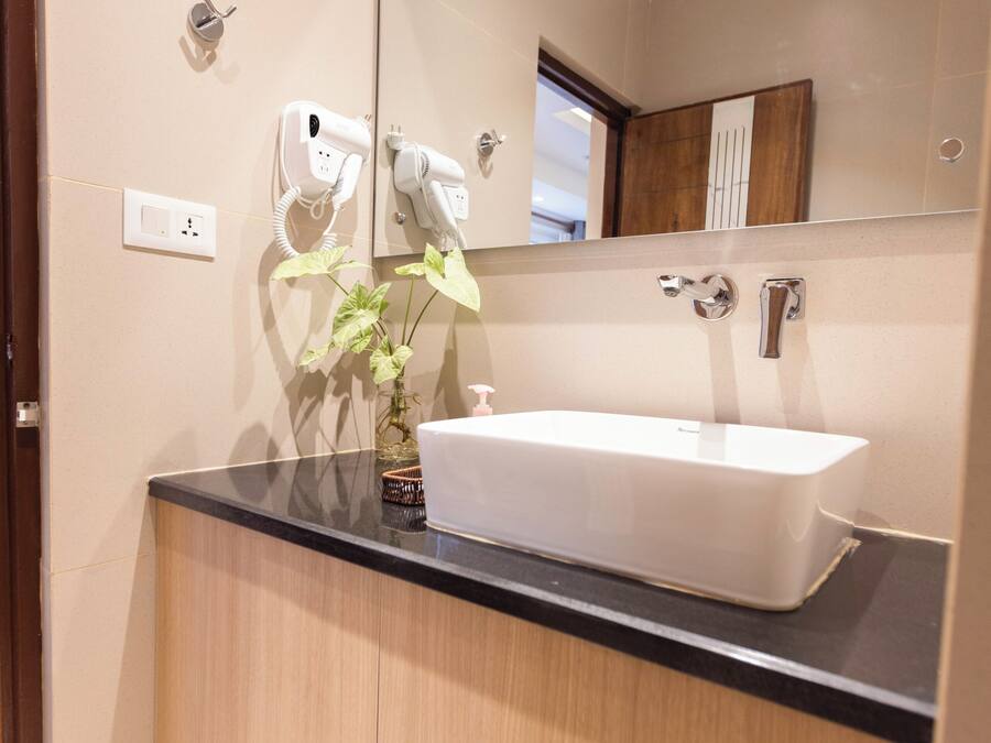 A modern bathroom with a large mirror, a white sink, and a wooden vanity.