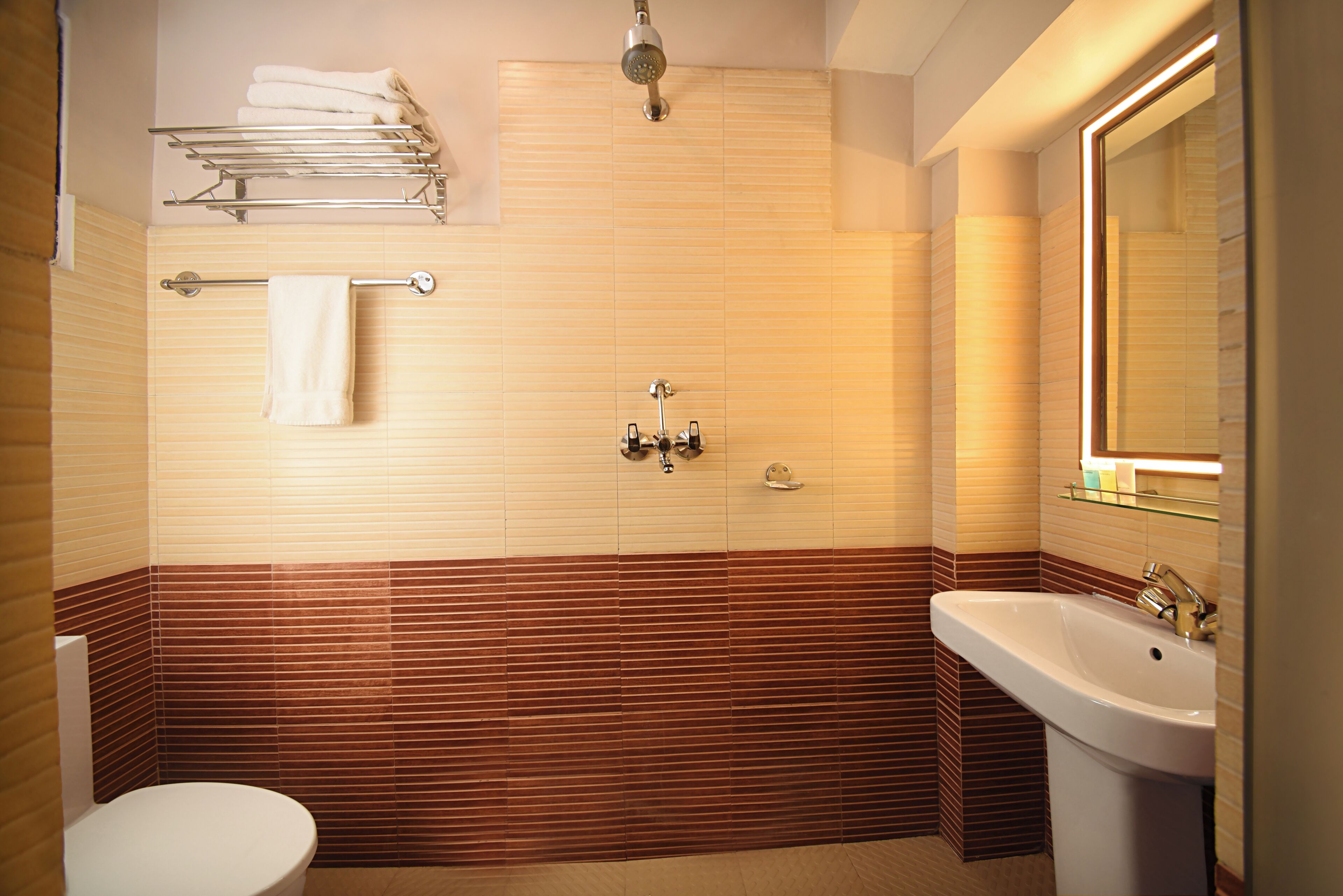 Une salle de bain comprenant des toilettes, un lavabo, une douche, un porte-serviettes et un miroir.