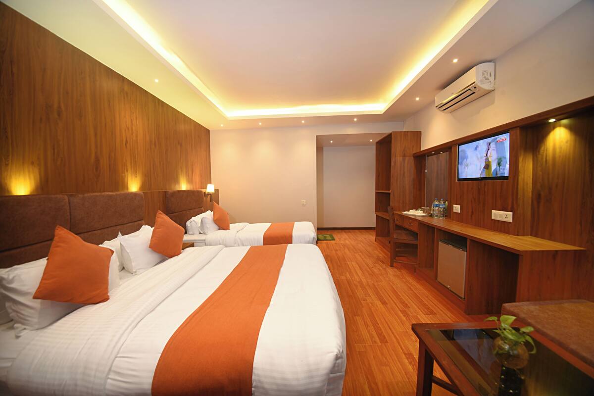 Een hotelkamer met twee bedden, een televisie, een bureau en een kleine keukenhoek.