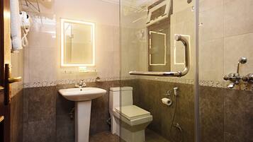 A modern bathroom with a glass-enclosed shower, a pedestal sink, a toilet, and a mirror with a lighted frame.