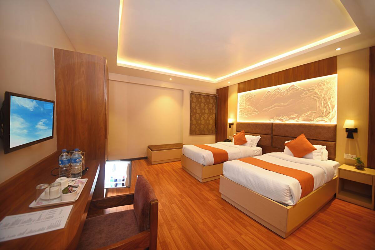 Een hotelkamer met twee bedden, een bureau en een televisie.