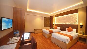 A hotel room with two beds, a desk, and a television.