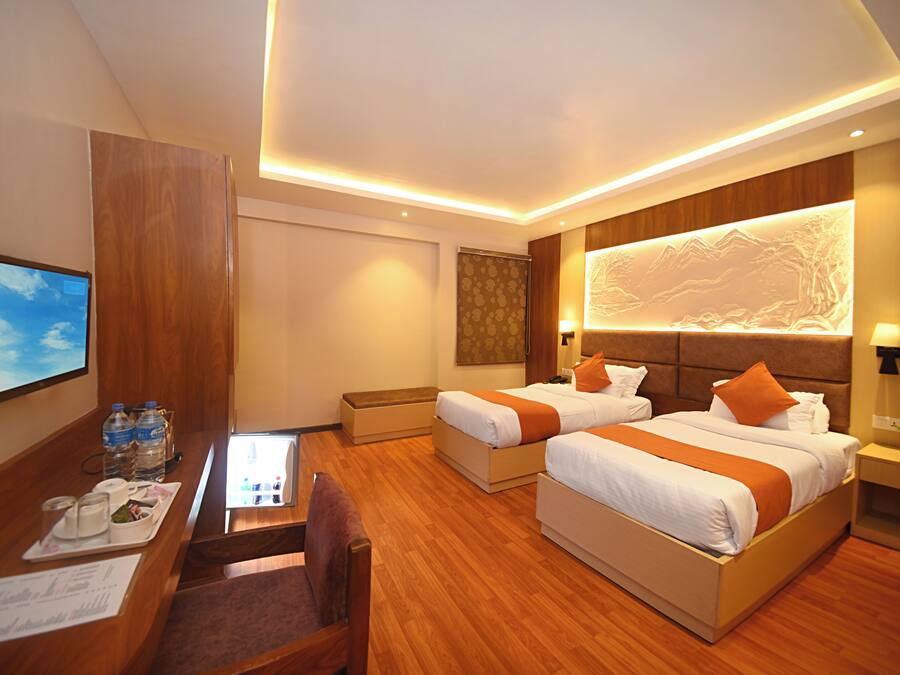 A hotel room with two beds, a desk, and a television.