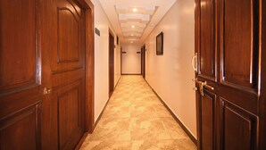 A hallway with wooden doors and a tiled floor. - Hotel Mums Home (Kathmandu)