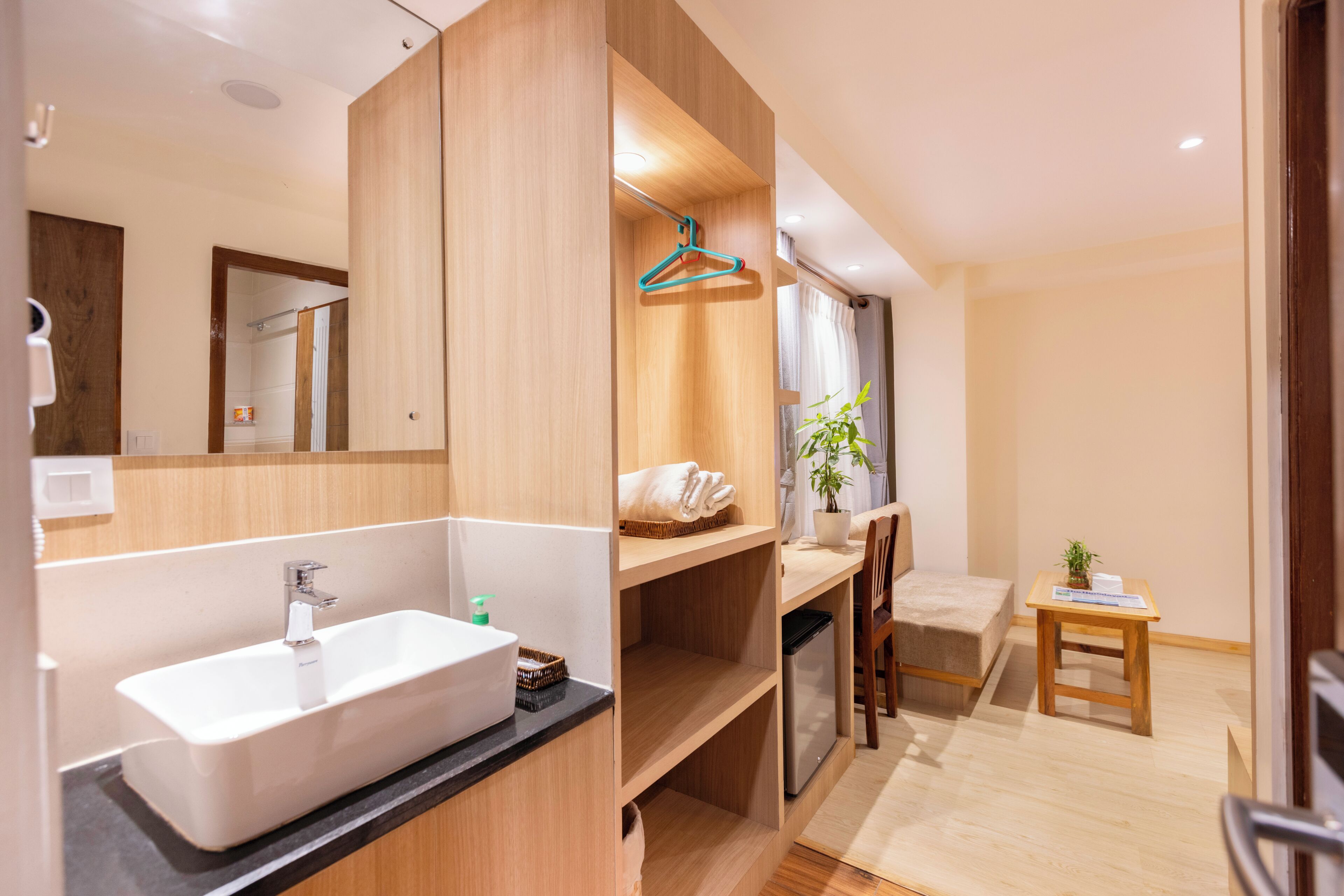 A modern bathroom with a large sink, mirror, and wooden shelving.