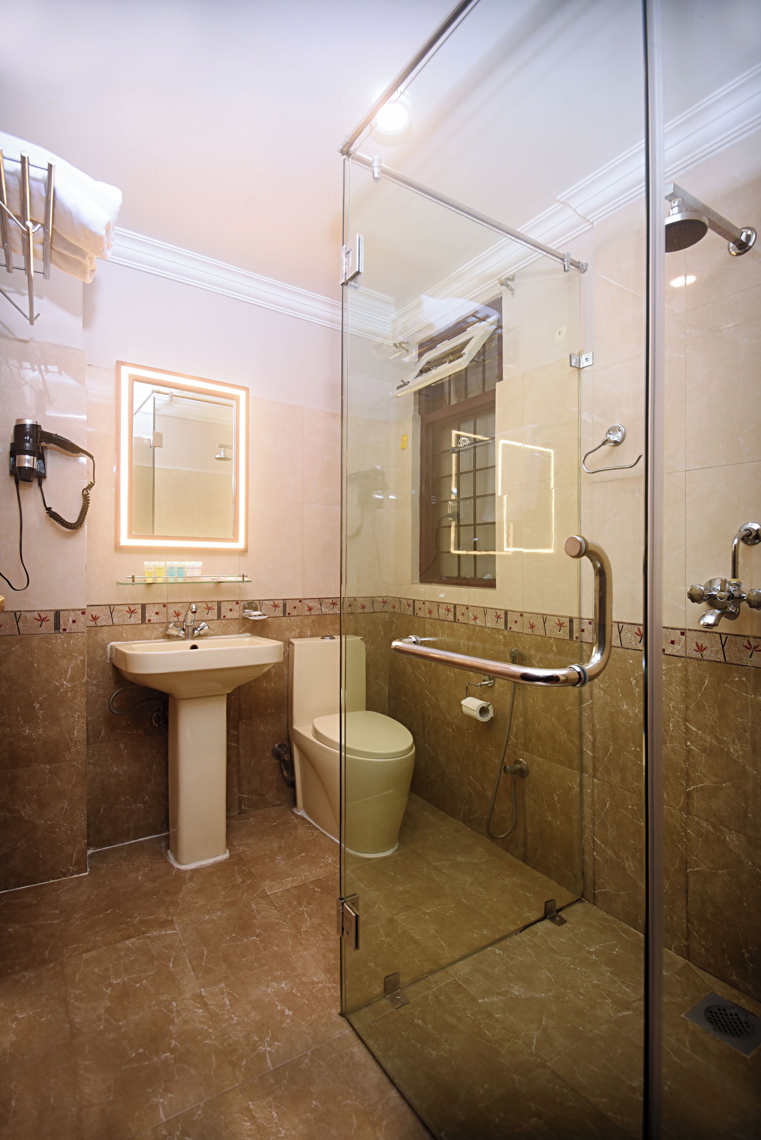 A modern bathroom with a glass-enclosed shower, a pedestal sink, and a toilet.
