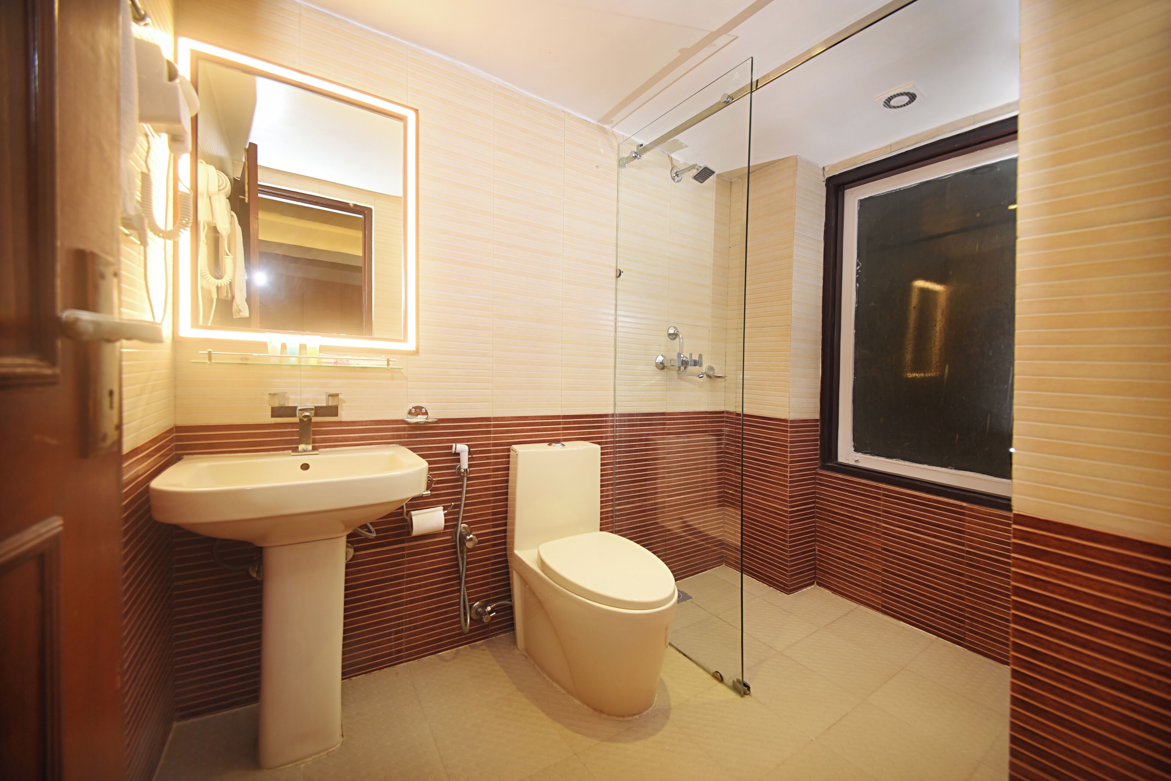 A modern bathroom with a glass-enclosed shower, a pedestal sink, and a toilet.