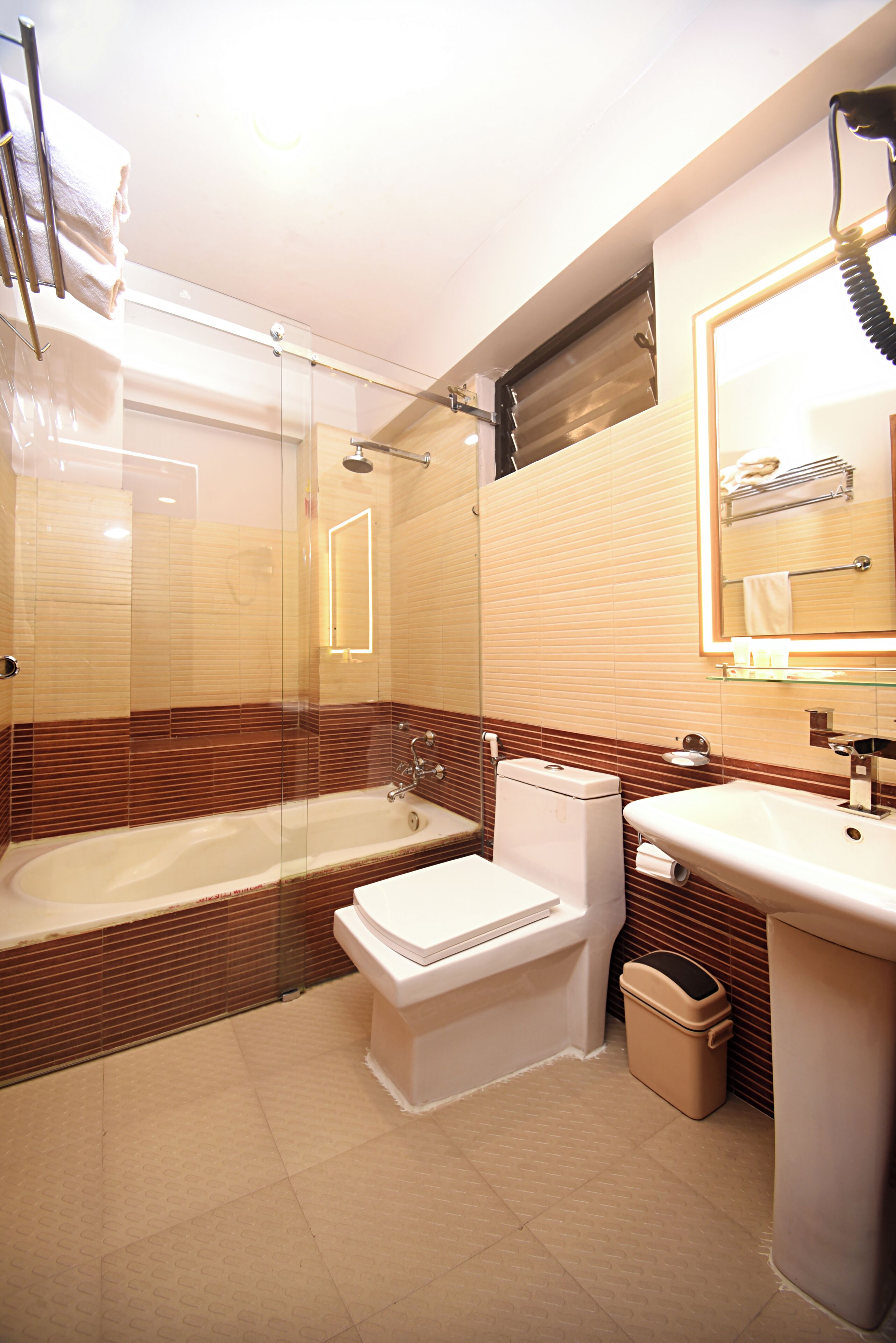 A modern bathroom with a glass-enclosed shower, a white toilet, and a sink with a mirror above it.