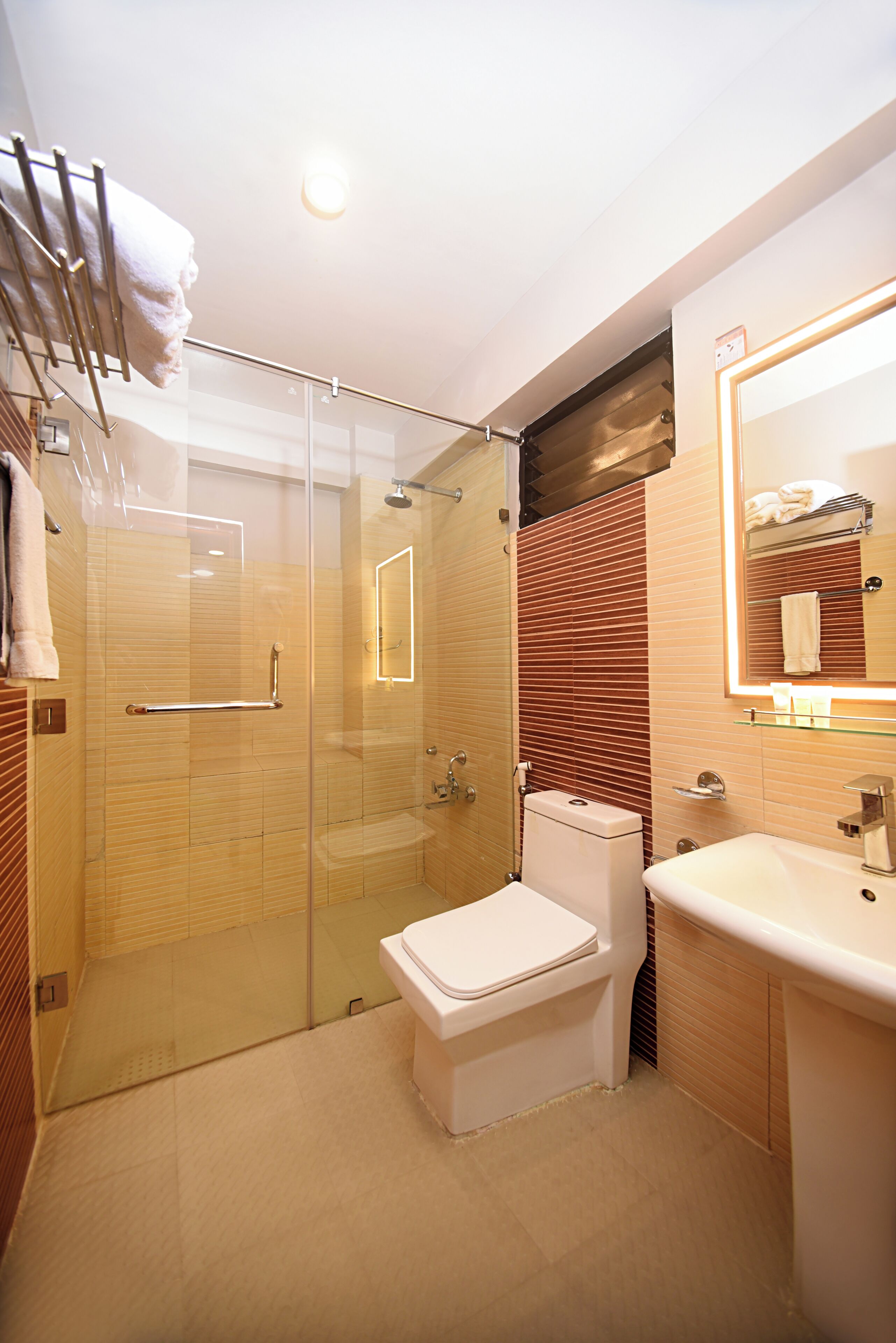 Un baño moderno con cabina de ducha de vidrio, inodoro blanco y lavabo con espejo.