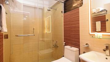 Un baño moderno con cabina de ducha de vidrio, inodoro blanco y lavabo con espejo.