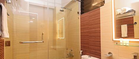 A modern bathroom with a glass shower enclosure, a white toilet, and a sink with a mirror above it.