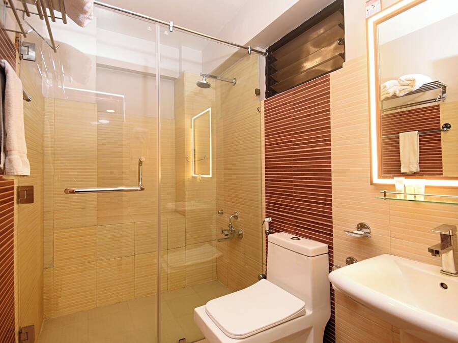 Un baño moderno con cabina de ducha de vidrio, inodoro blanco y lavabo con espejo.