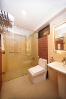 Un baño moderno con cabina de ducha de vidrio, inodoro blanco y lavabo con espejo.