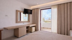 Une chambre d’hôtel moderne dotée d’un grand lit, d’un téléviseur fixé sur une console en bois, d’une porte-fenêtre coulissante donnant sur un balcon et d’un petit coin salon.