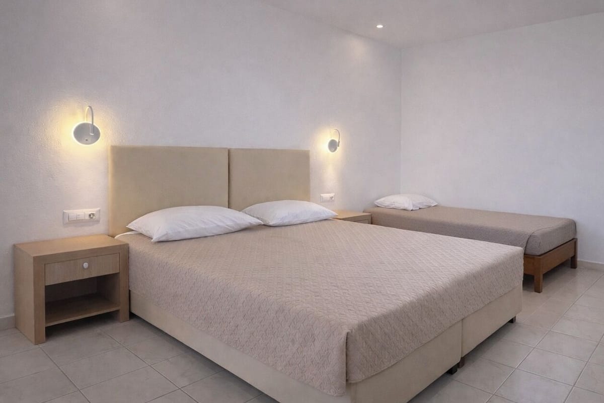 Una habitación de hotel con una cama grande, dos mesitas de noche e iluminación en la pared.