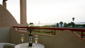 Un balcon avec une table dressée pour deux personnes, agrémentée d’une bouteille de vin et de deux verres.